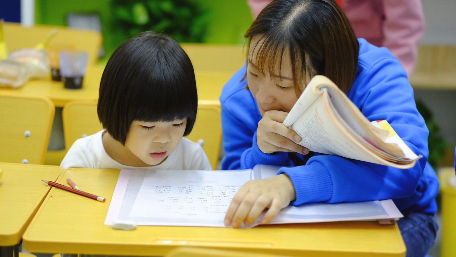 先生と一緒に笑顔で学ぶ子ども